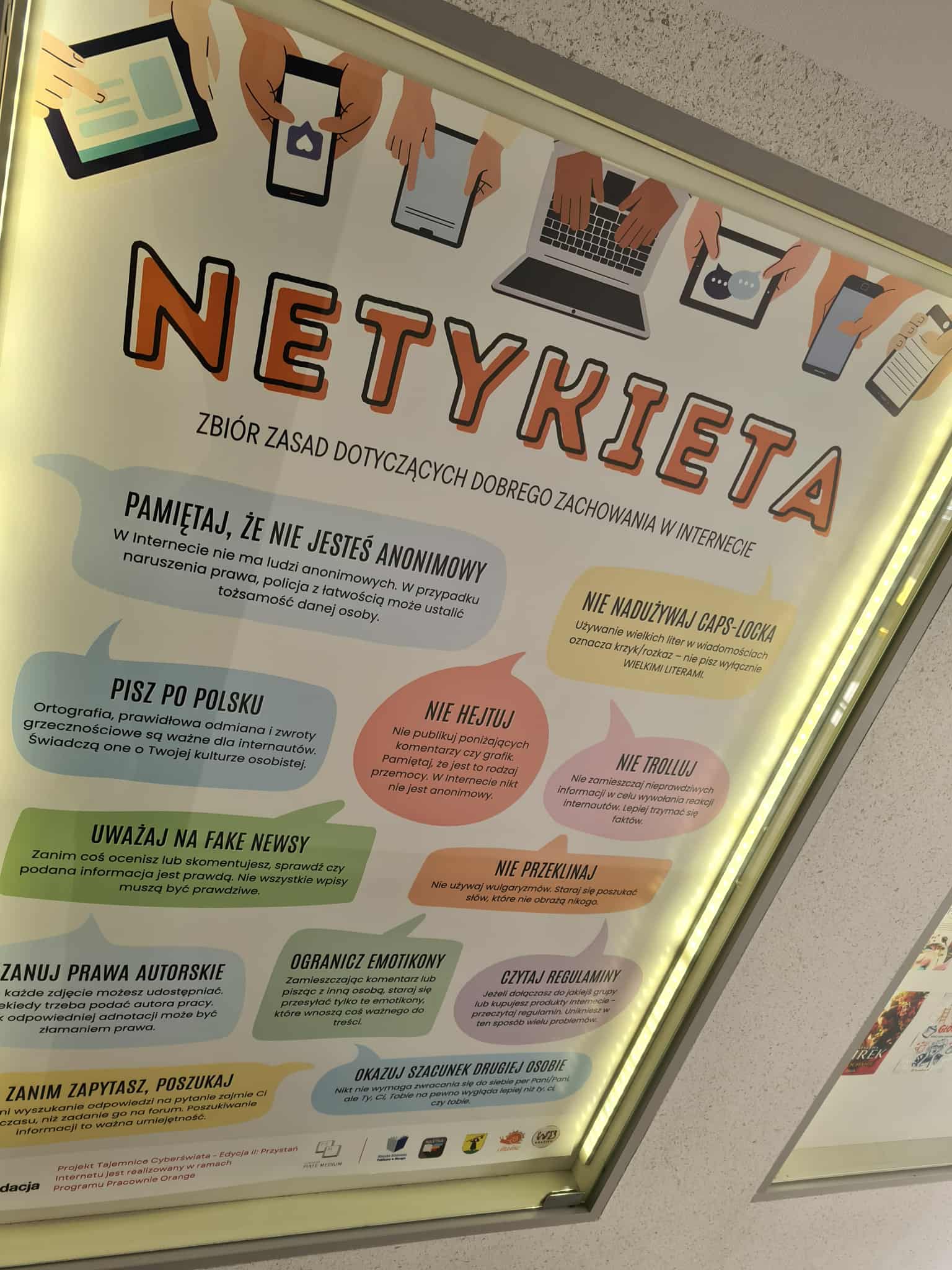 Zbliżenie na plakat „Netykieta” przedstawiający zasady dobrego zachowania w internecie, m.in. „nie hejtuj”, „nie trolluj”, „uważaj na fake newsy”, „pisz po polsku”.