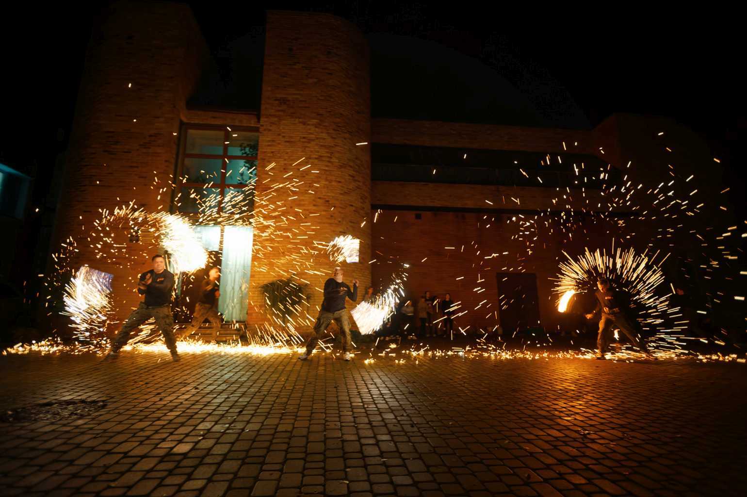 Widowisko fireshow przed biblioteką – tancerze żonglują płonącymi rekwizytami.