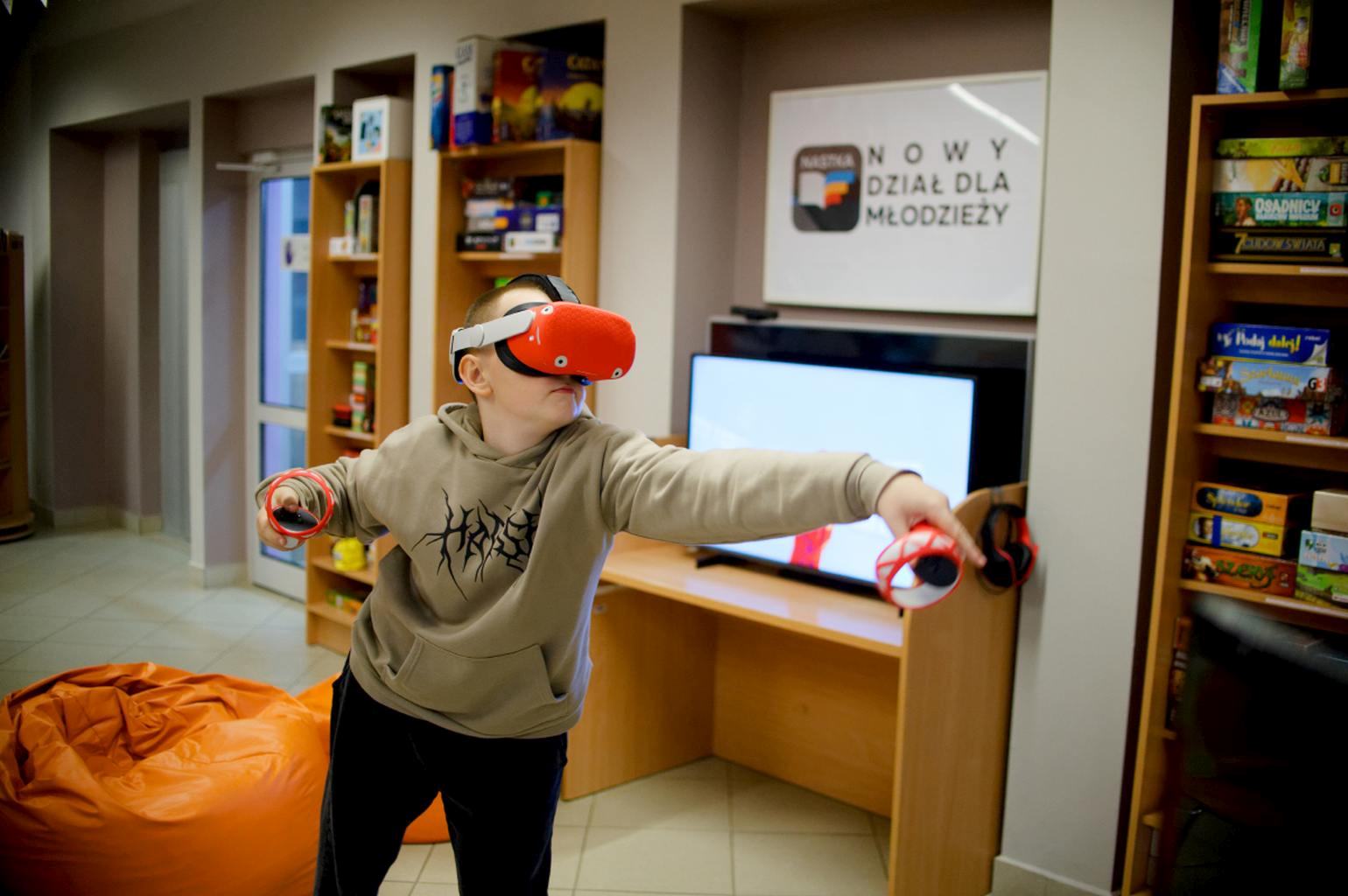 Chłopiec gra w grę VR w dziale dla młodzieży biblioteki.