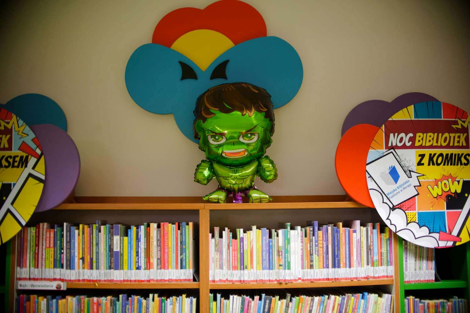 Balonowy Hulk nad półką z książkami i dekoracje „Noc Bibliotek z komiksem”.