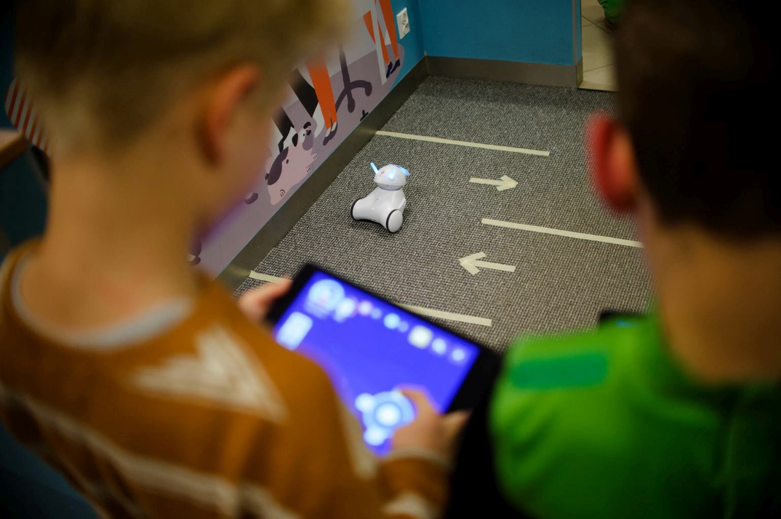Dwóch chłopców steruje małym robotem za pomocą tabletów.