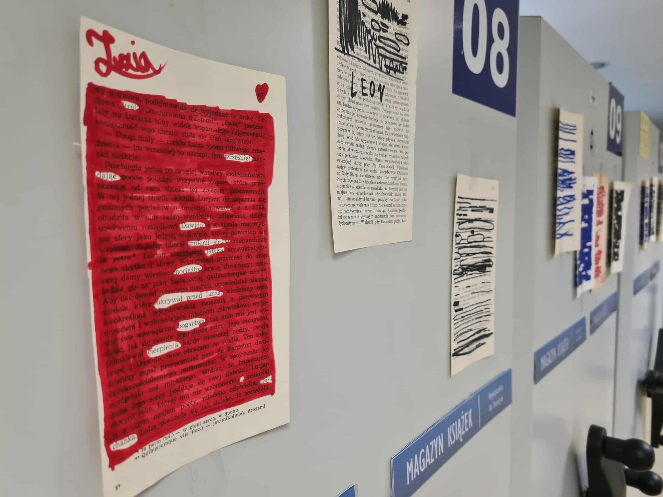 Kolorowe prace blackout poetry wyeksponowane na szafkach w bibliotecznym magazynie.