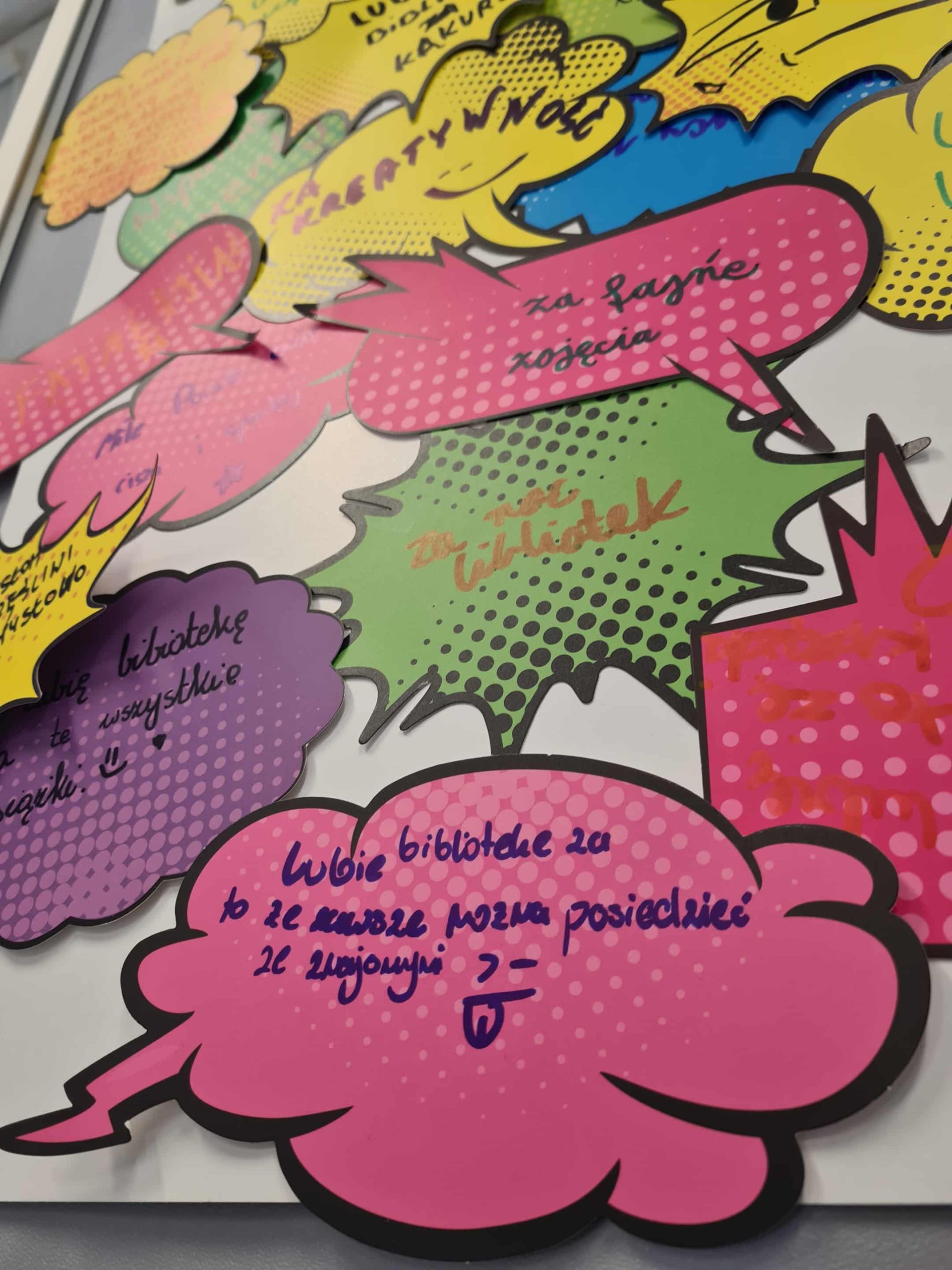 Kolorowe chmurki z wypowiedziami uczestników akcji „Lubię bibliotekę za...” – ręcznie zapisane powody sympatii do biblioteki.