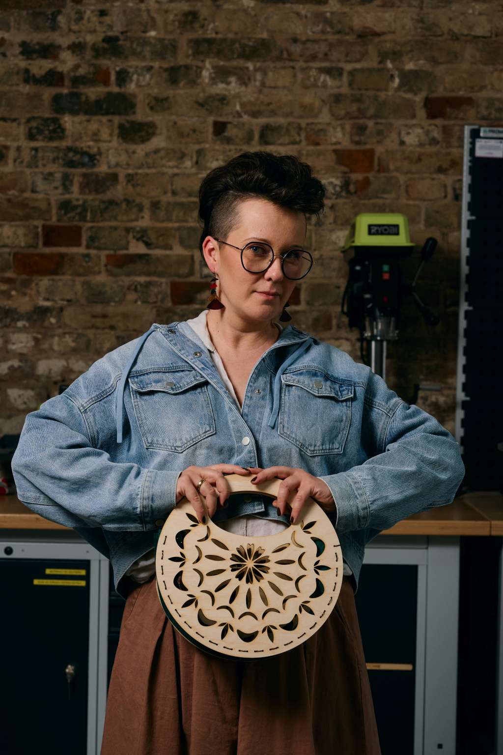Osoba prezentuje okrągłą drewnianą torebkę o ażurowym wzorze.