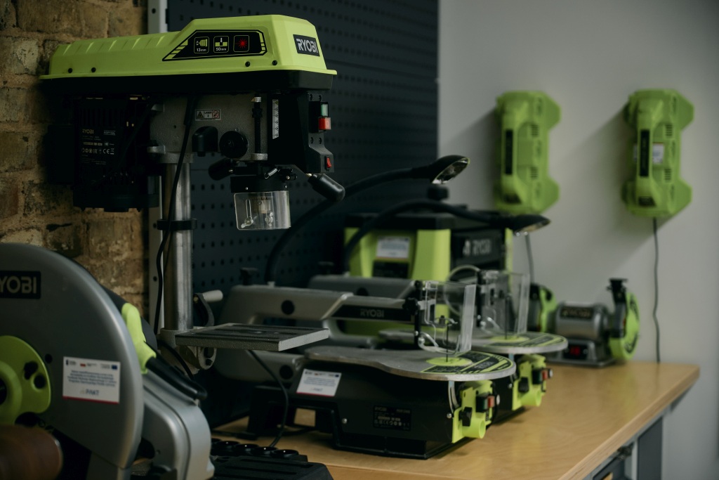 Elektronarzędzia marki Ryobi ustawione na stole w warsztacie.