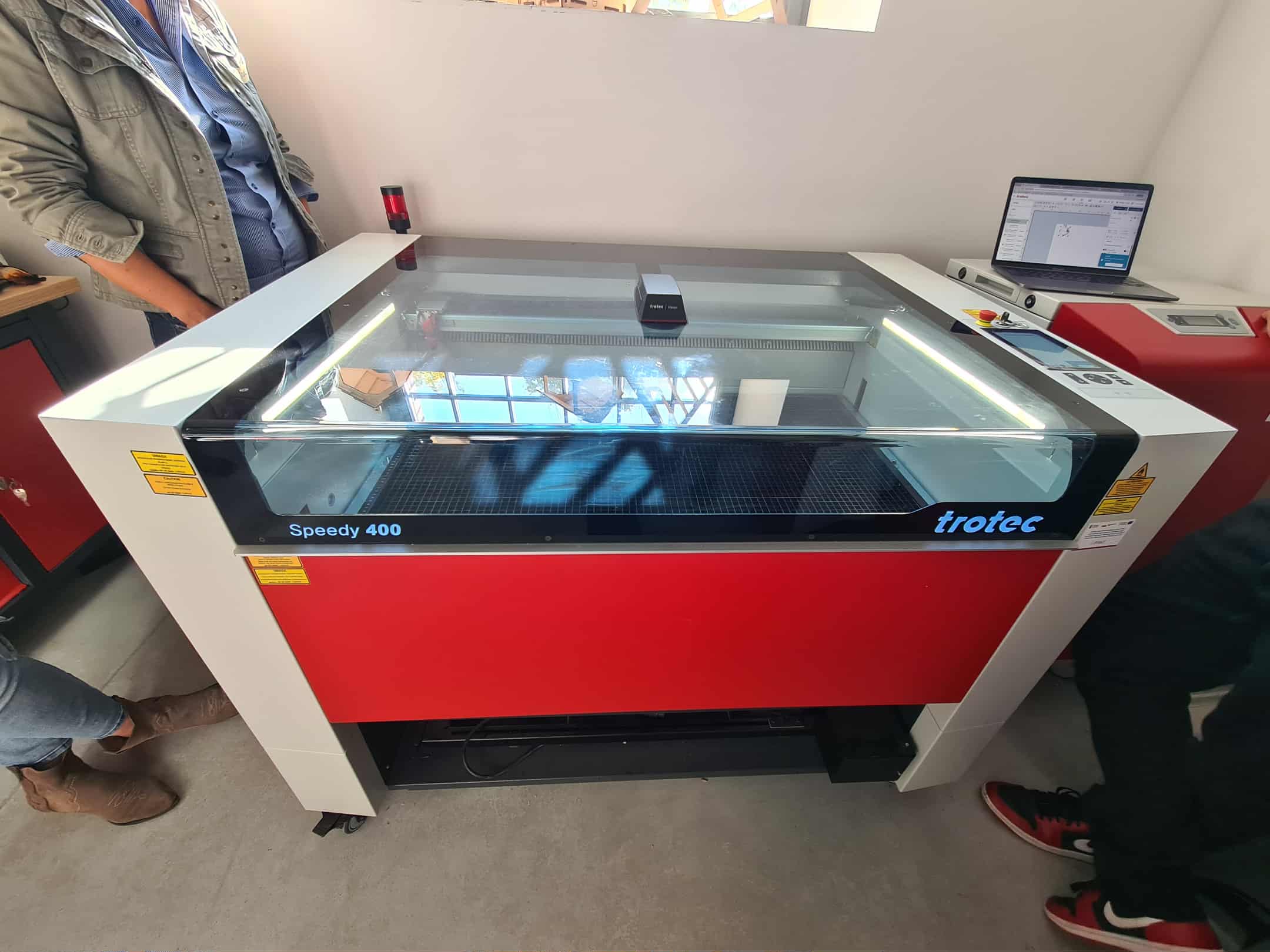 Laser tnący Trotec Speedy 400 gotowy do pracy, obok laptop z projektem.