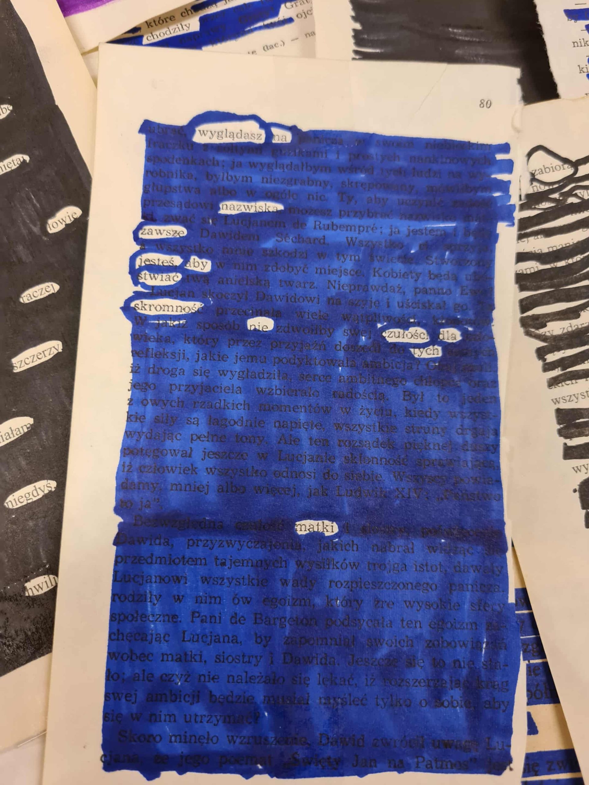 Zbliżenie na czerwoną pracę blackout poetry z wyraźnie widocznymi słowami wybranymi z tekstu książki.