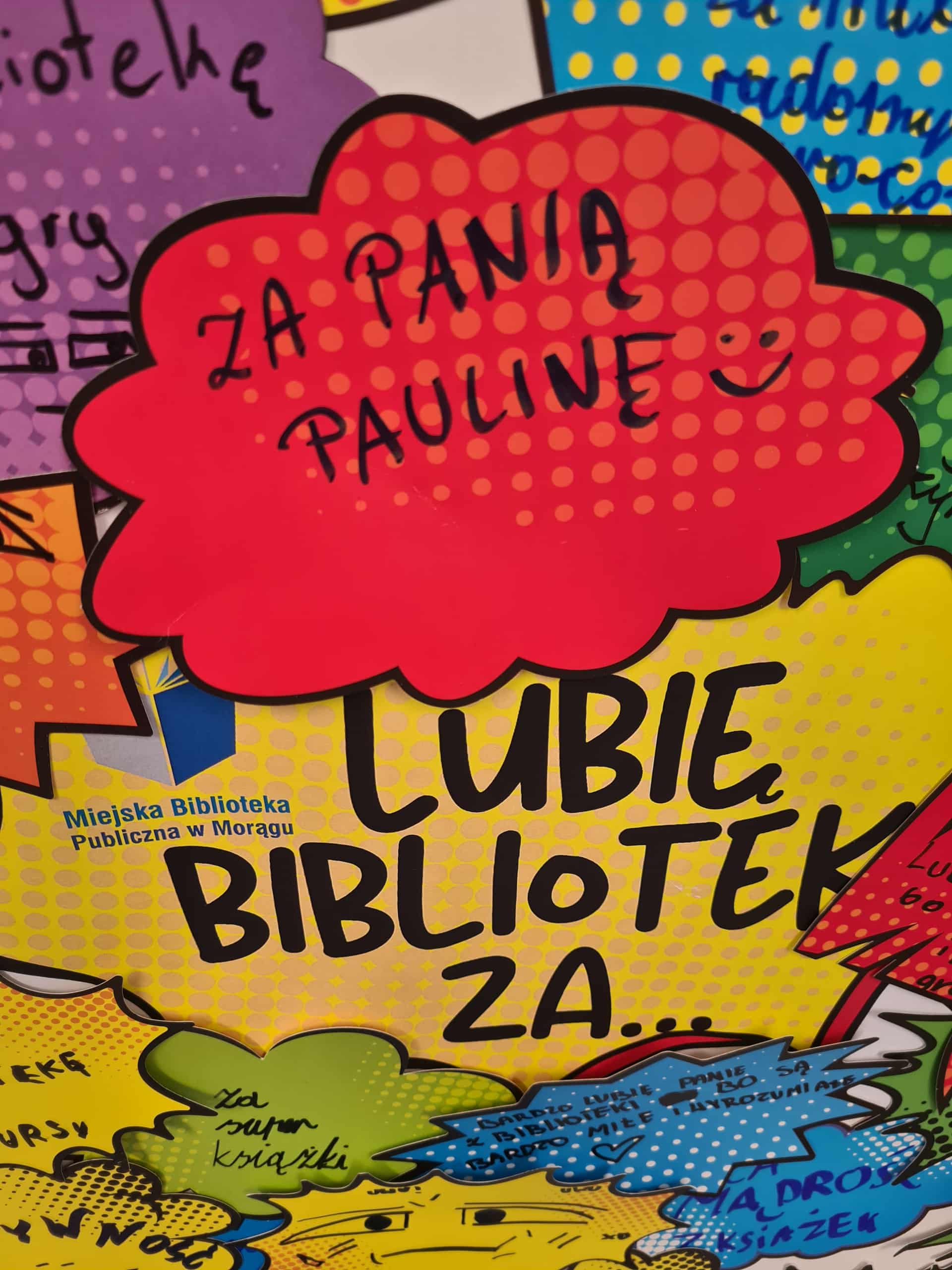 Czerwona chmurka z napisem „Za panią Paulinę” na tle kolorowej planszy z napisem „Lubię bibliotekę za...”.