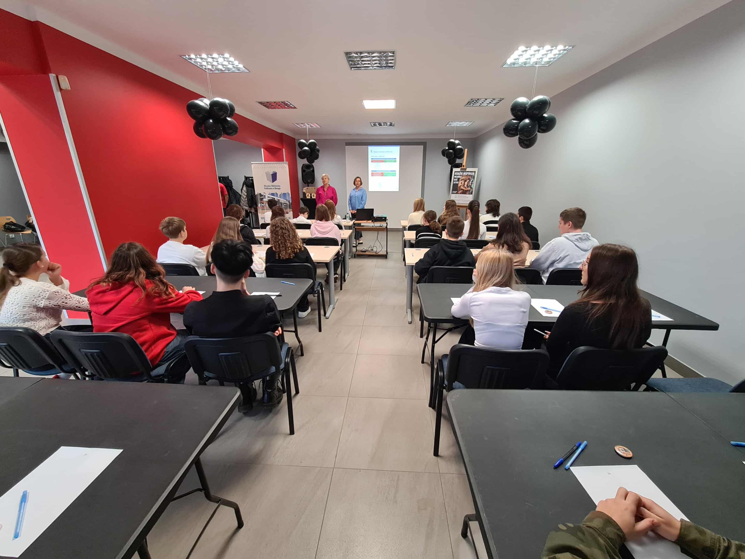 Widok sali podczas rozpoczęcia konkursu, uczestnicy słuchają prowadzącej.