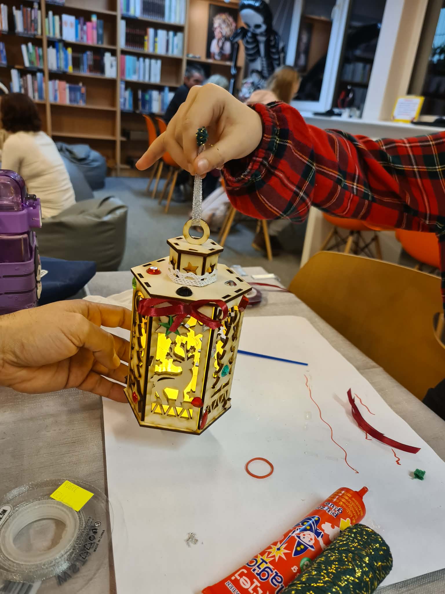 Ozdobiony lampion z motywem świątecznym i ciepłym światłem w środku.