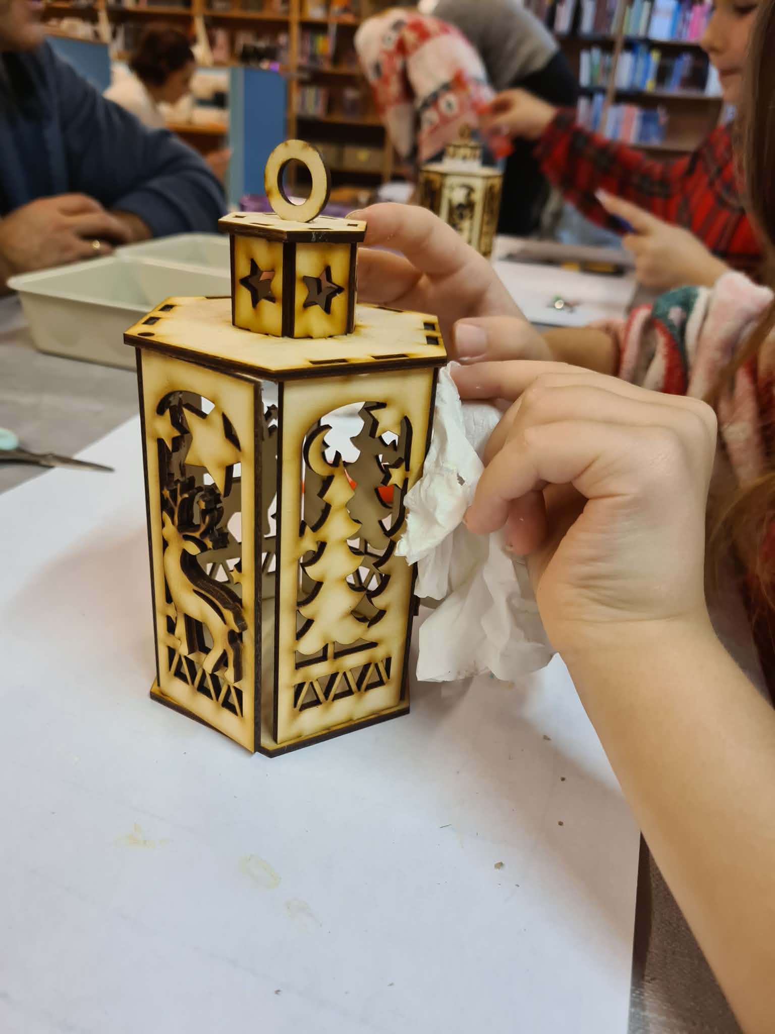 Gotowy, podświetlony lampion świąteczny trzymany w dłoniach uczestnika.