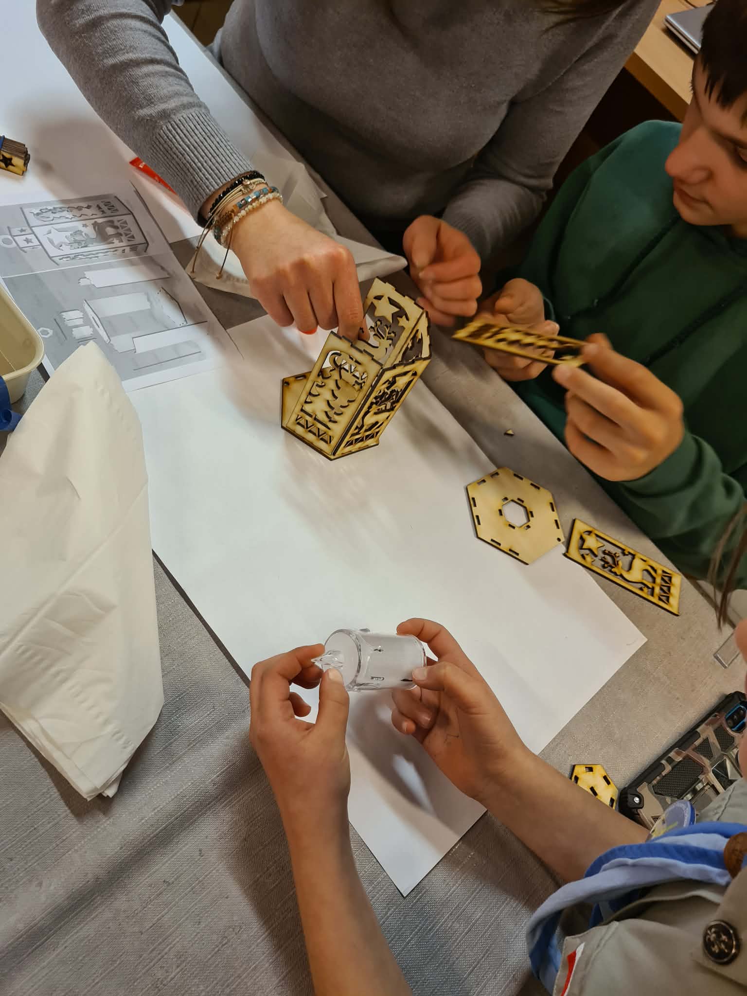 Dziecko składa elementy drewnianego lampionu według instrukcji.