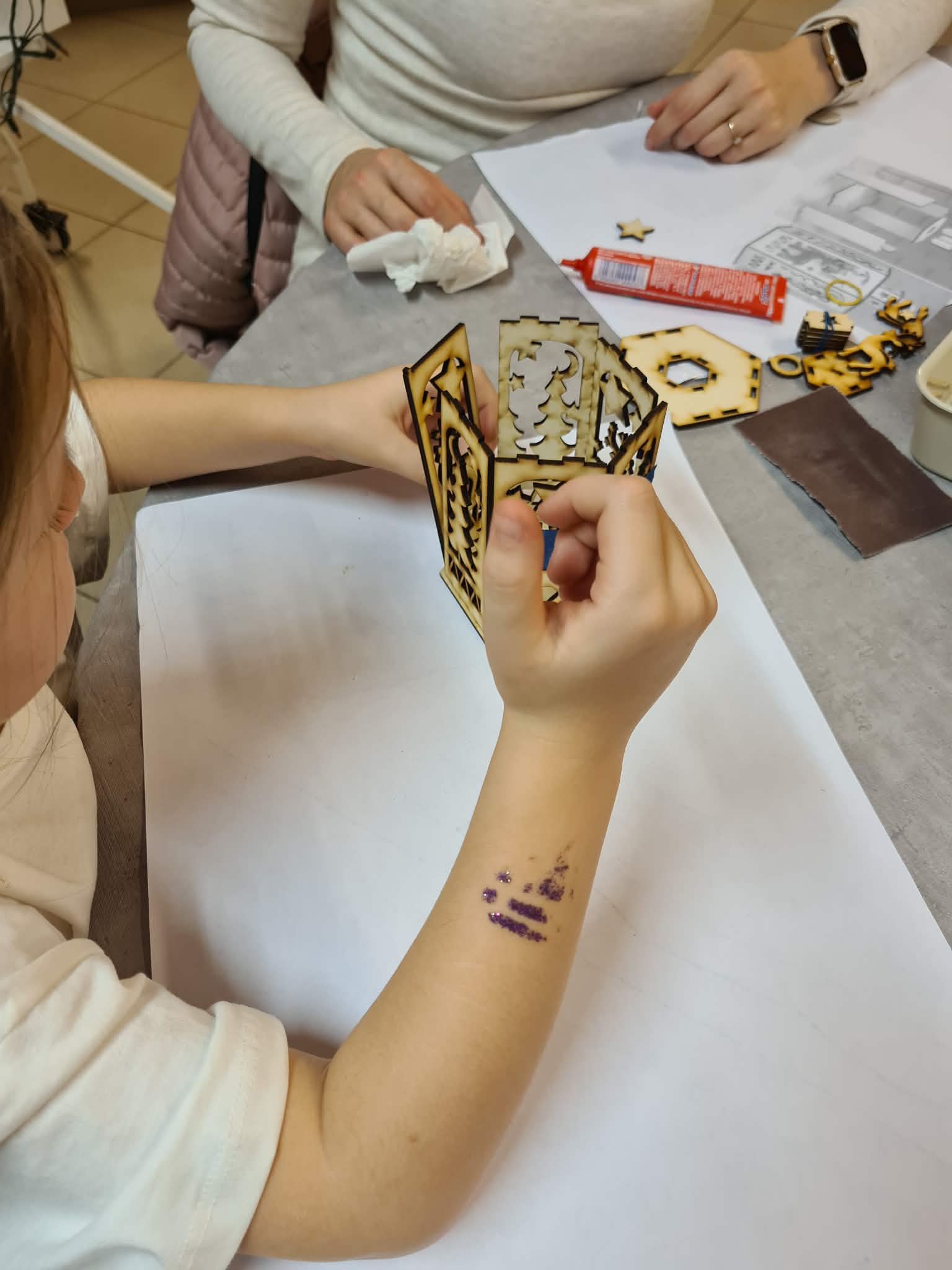 Dziecko składa elementy drewnianego lampionu według instrukcji.