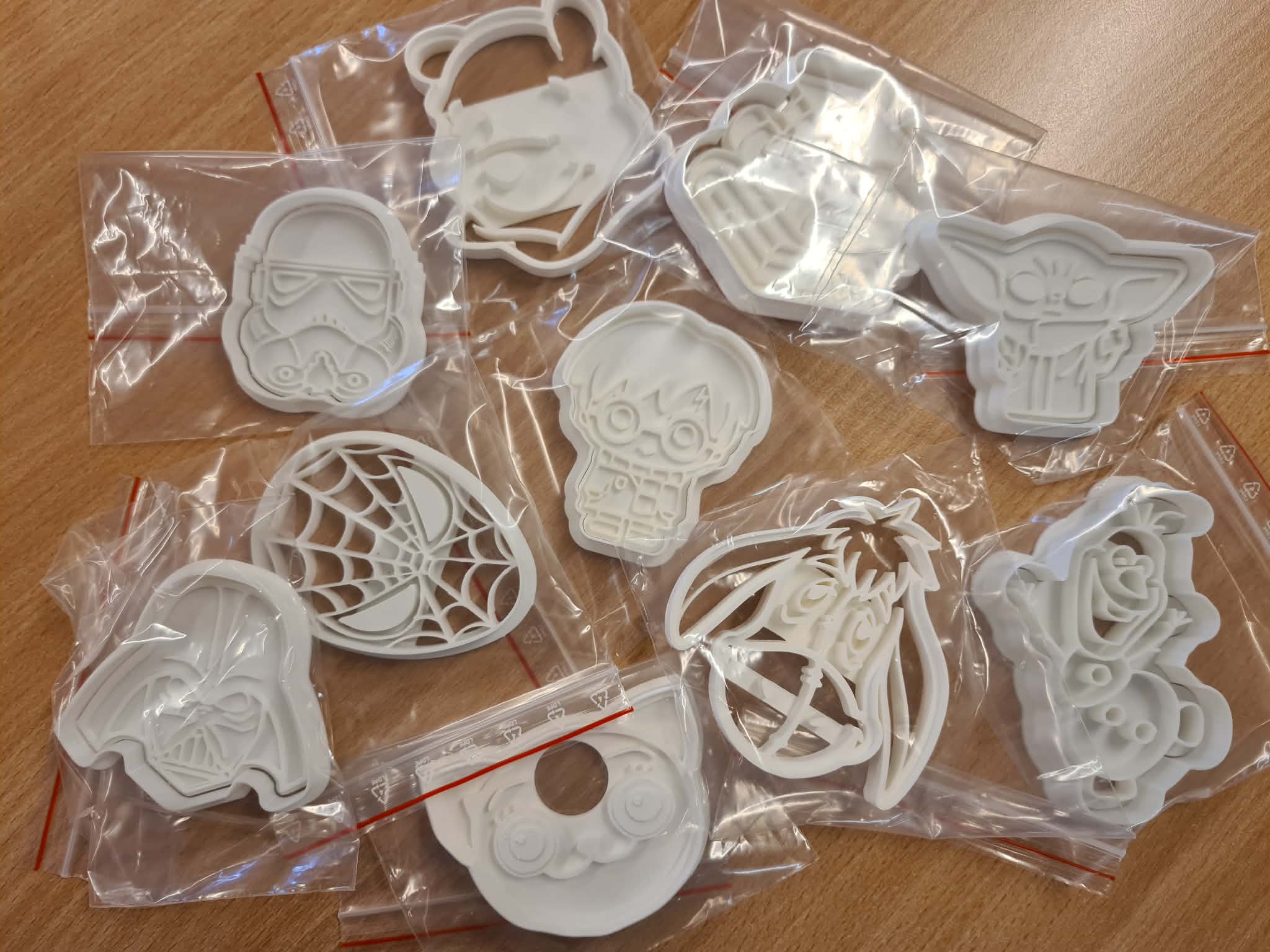 Zestaw różnych foremek 3D o popkulturowych kształtach (m.in. Vader, Stormtrooper, Harry Potter), rozłożonych na stole.