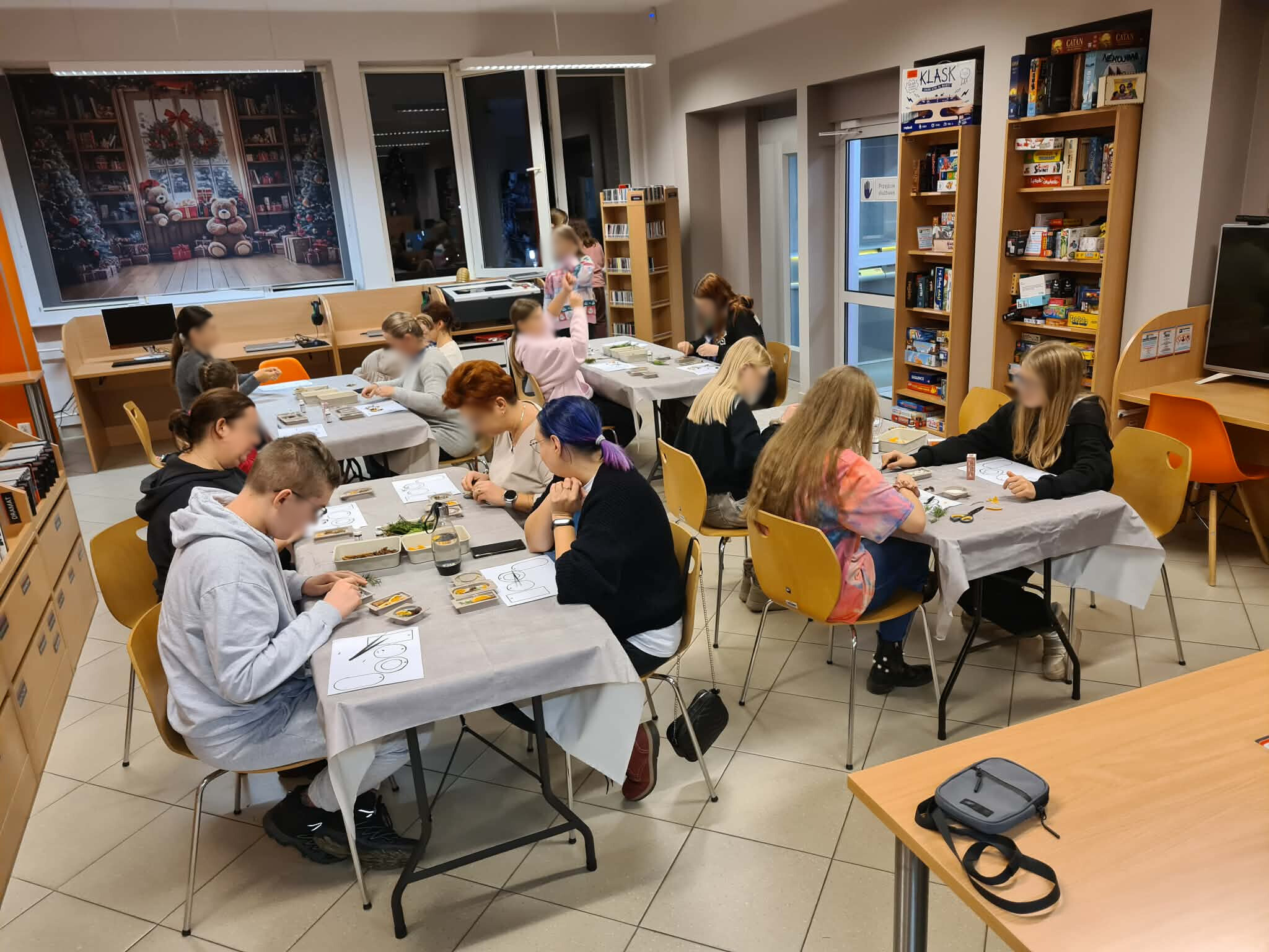 Warsztaty rękodzielnicze przy stołach w bibliotece.