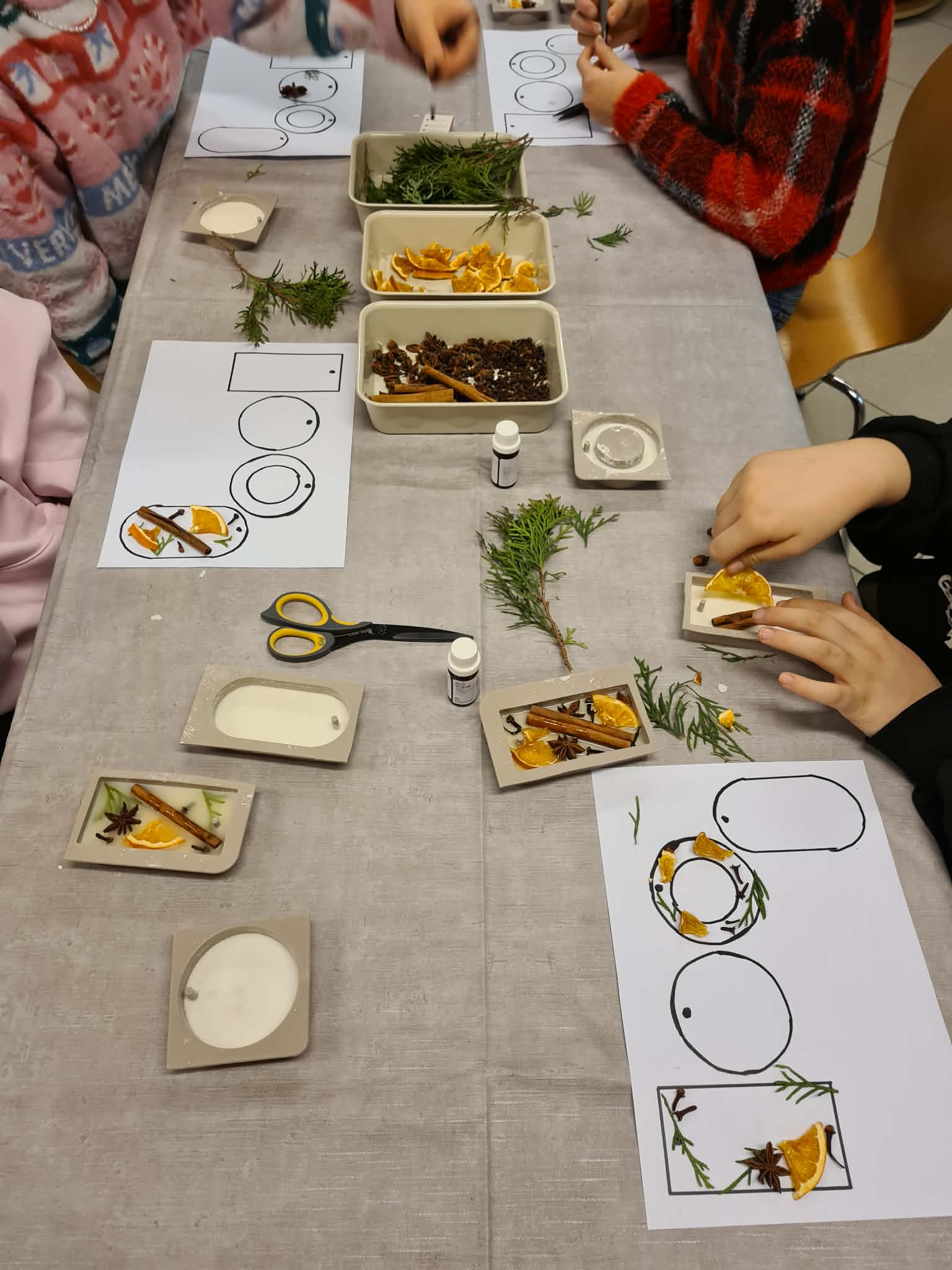 Dzieci i dorośli pracują nad świątecznymi tabliczkami zapachowymi.