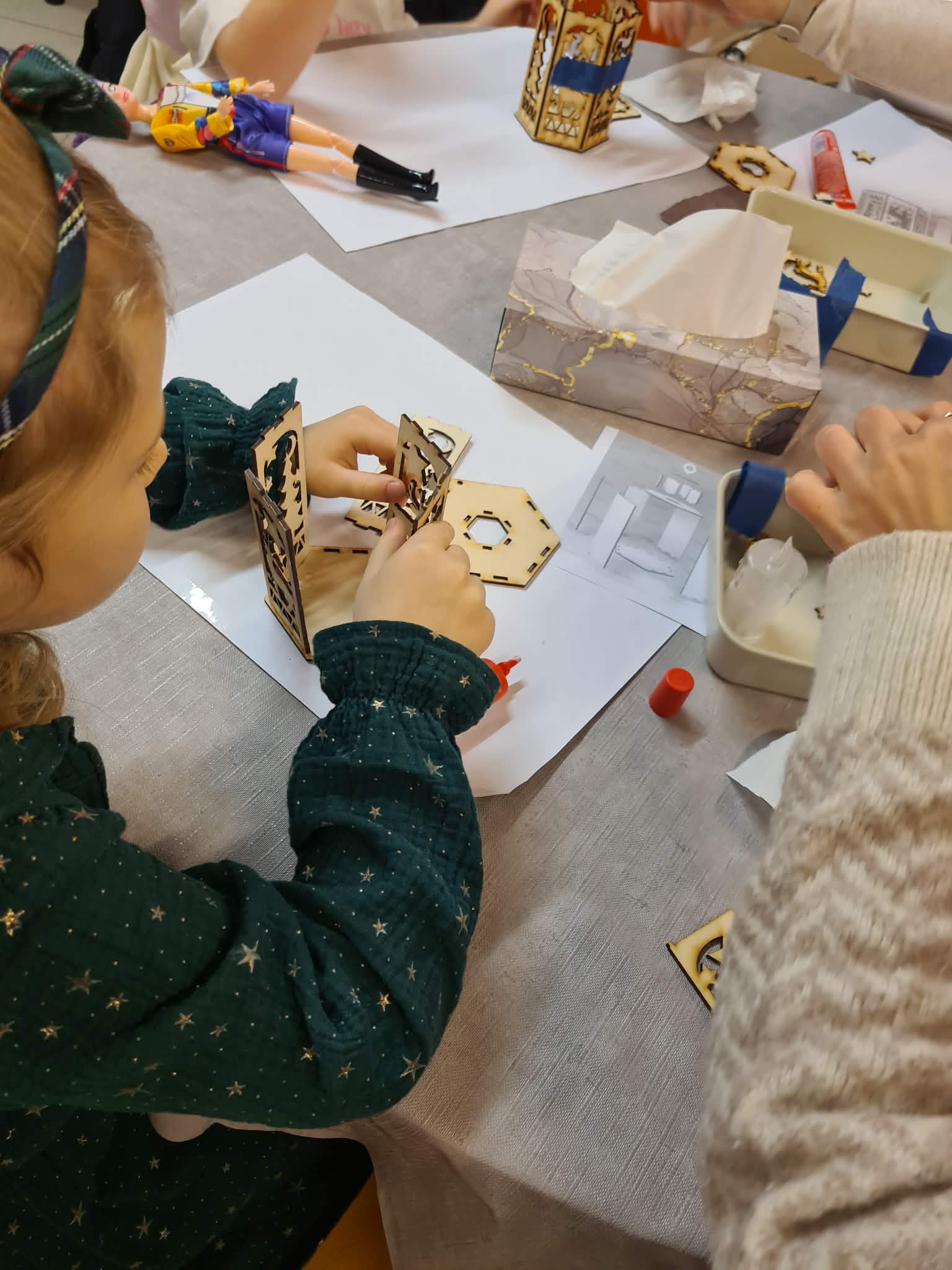 Dziecko składa drewniane elementy latarenki według instrukcji.