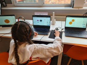 Uczestniczka w słuchawkach pracuje przy laptopie z programem do projektowania 3D.