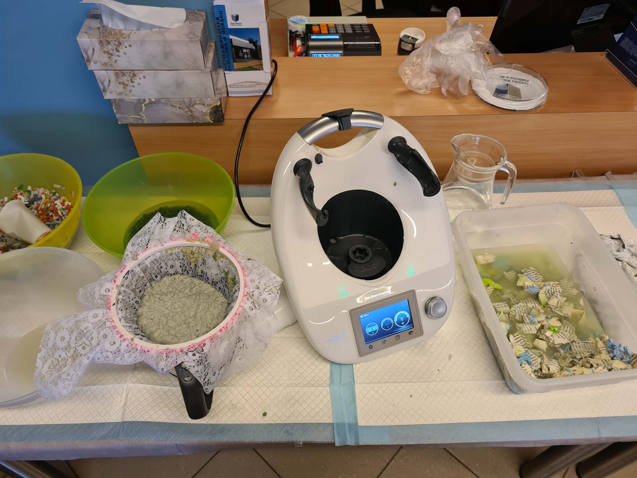 Stanowisko do papieru czerpanego z masą papierową, miskami i urządzeniem kuchennym.