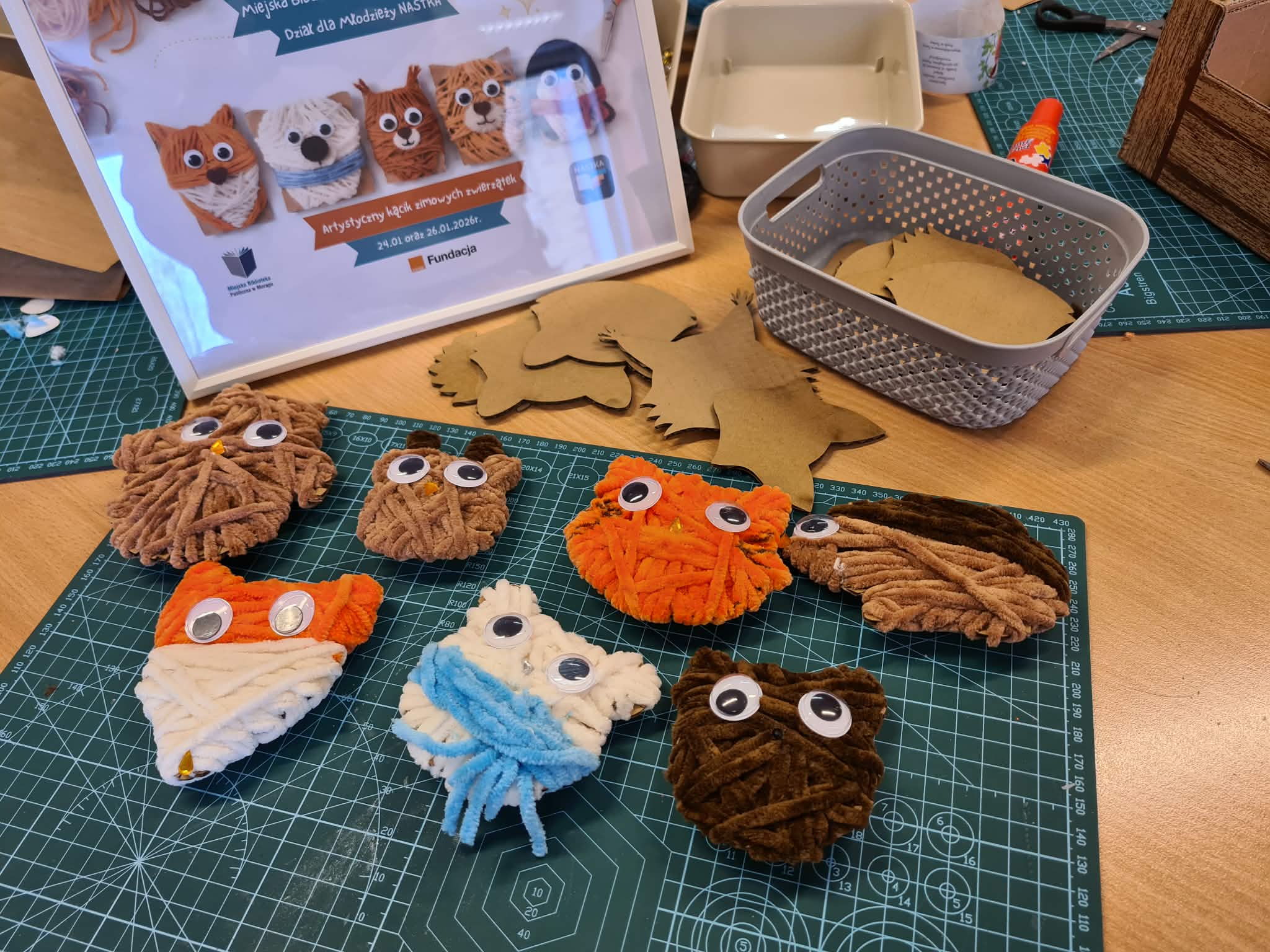Gotowe włóczkowe zwierzątka ułożone na macie do cięcia.