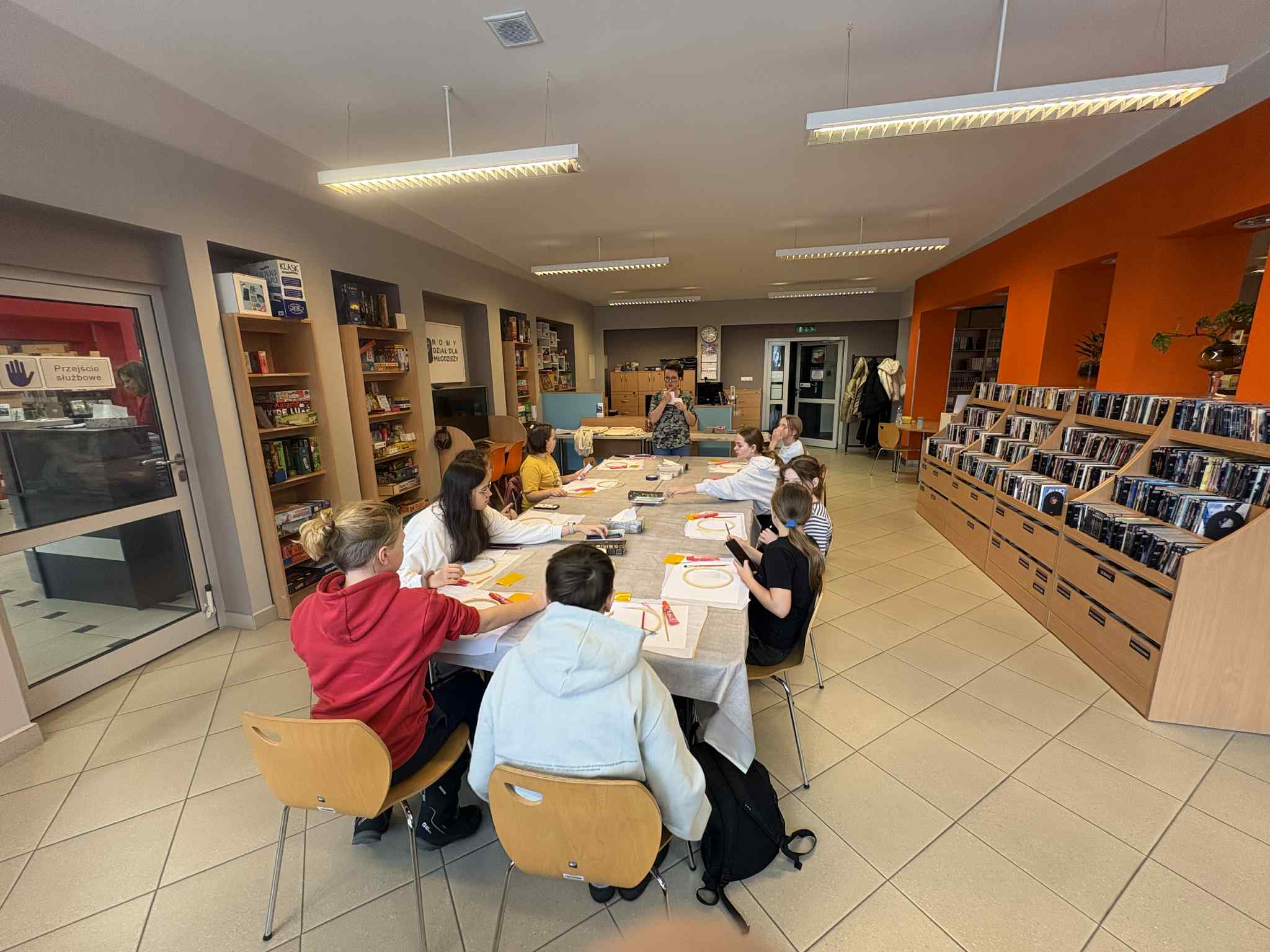 Szeroki plan: grupa dzieci pracuje przy dużym stole w bibliotece.