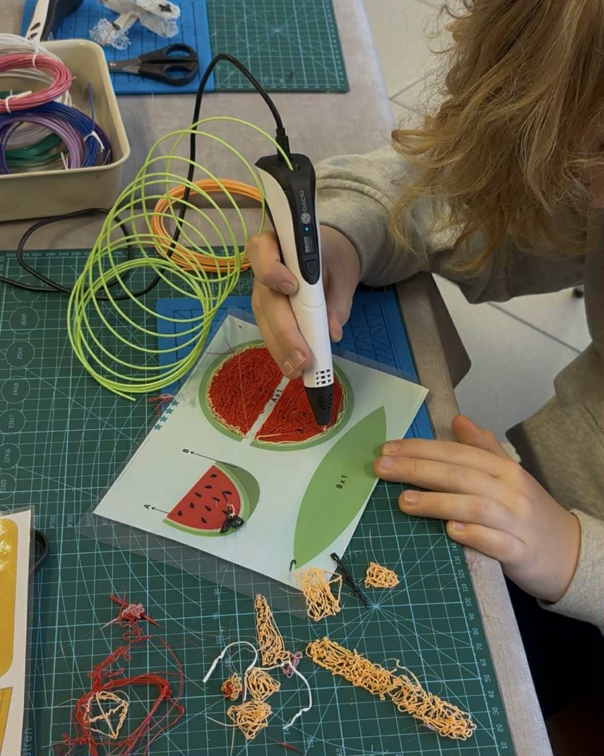 Osoba używa długopisu 3D do wypełniania kształtu arbuza.