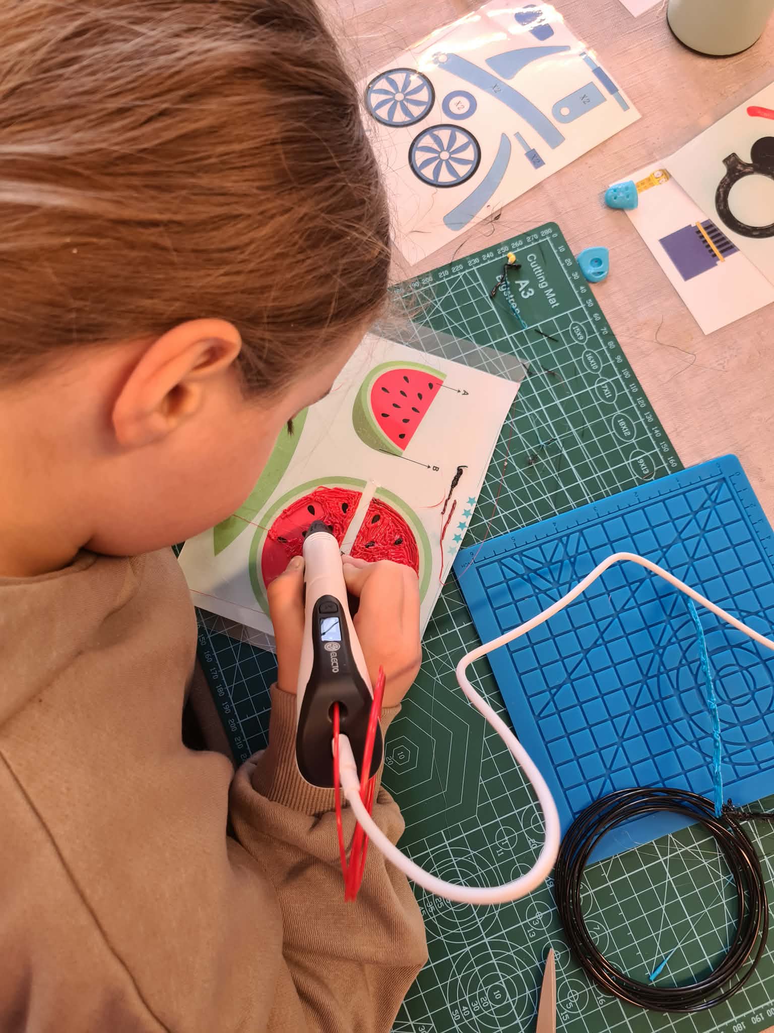 Osoba używa długopisu 3D do wypełniania kształtu arbuza.