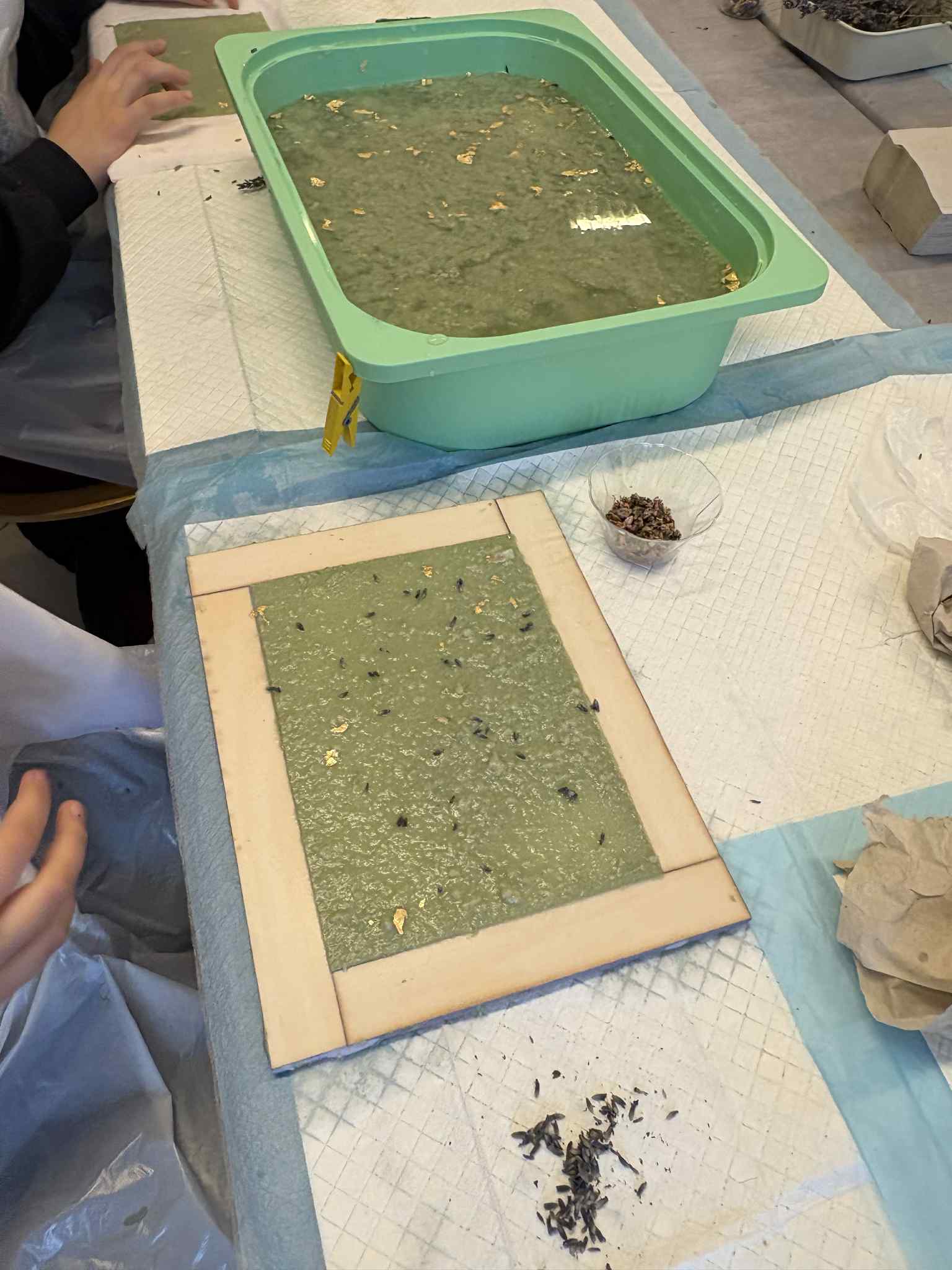 Arkusz świeżo czerpanego papieru z dodatkami roślinnymi na ramie.