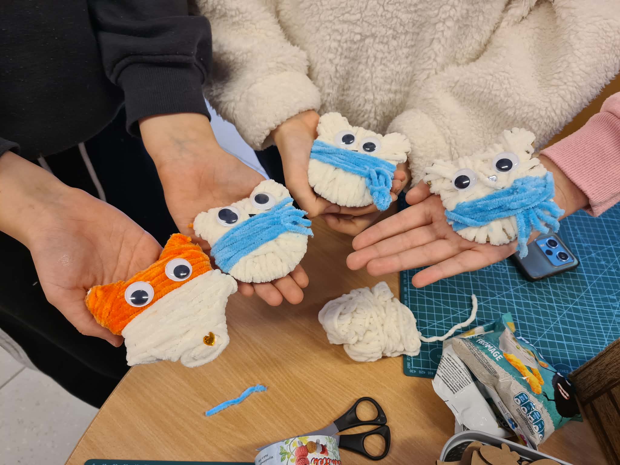 Kilka gotowych włóczkowych zwierzątek trzymanych w dłoniach uczestników.