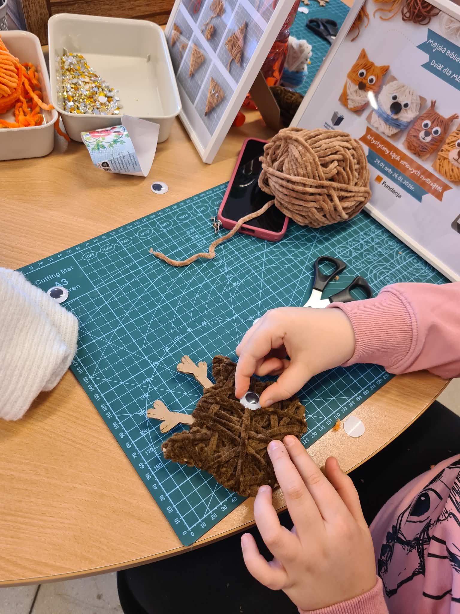 Przyklejanie ruchomego oczka do włóczkowego zwierzątka.