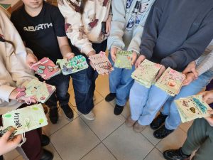 Grupa dzieci trzyma w dłoniach własnoręcznie wykonane książeczki z papieru czerpanego.