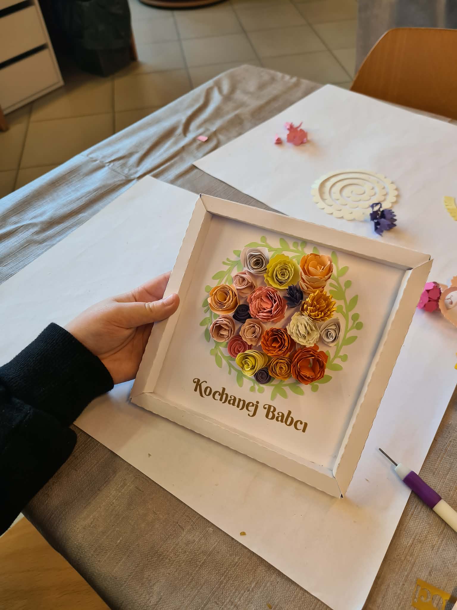 Gotowa ramka z kolorowymi papierowymi kwiatami i napisem „Kochanej Babci”.