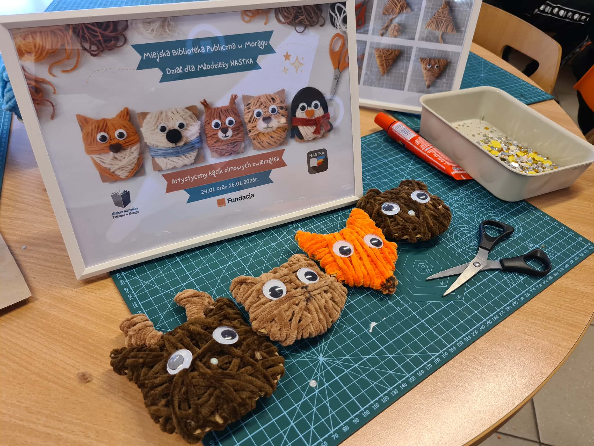 Dziecko owija włóczkę wokół kartonowej formy zwierzątka.