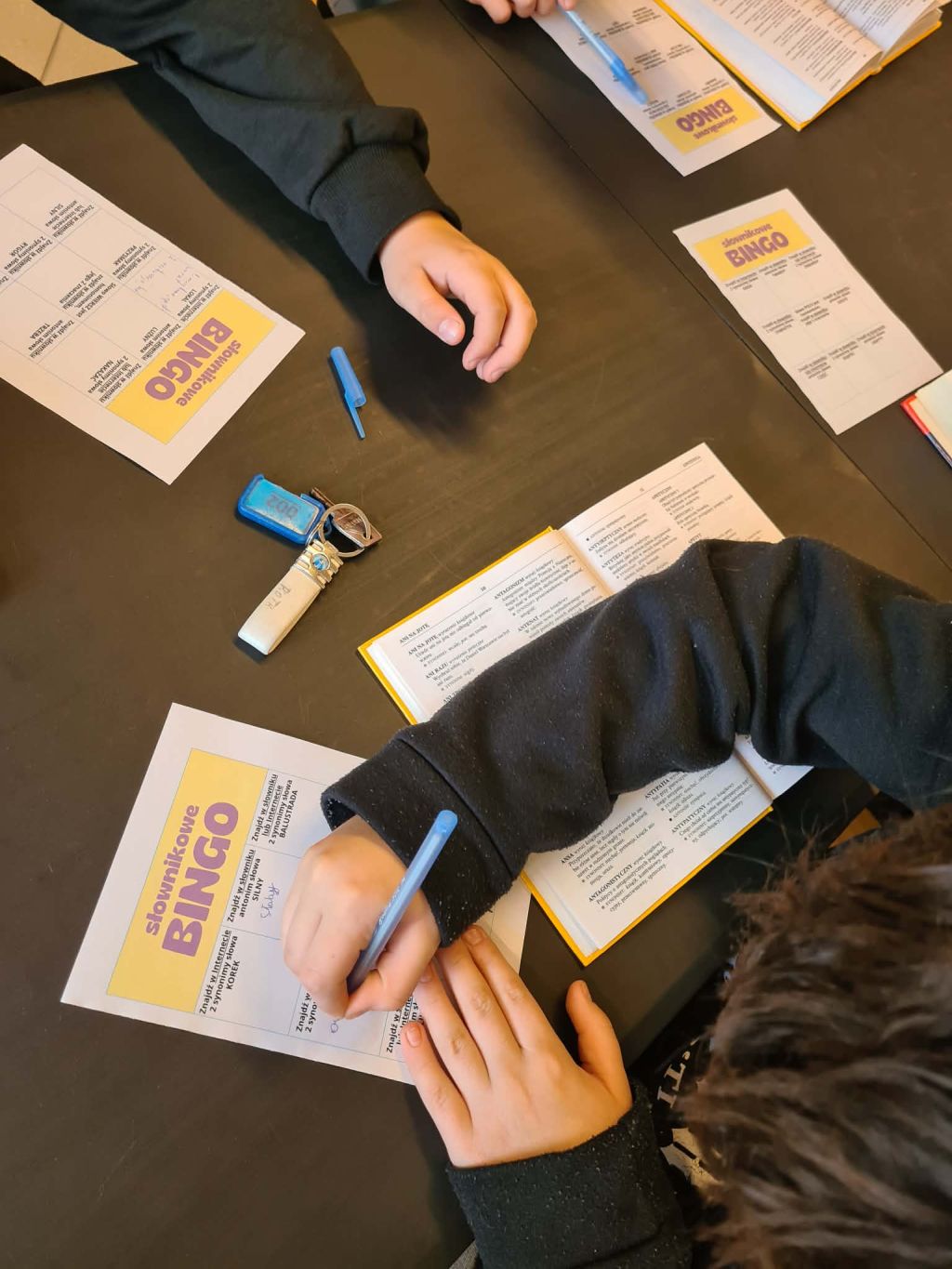 Widok z góry na ręce dziecka wypełniającego kartę do gry 