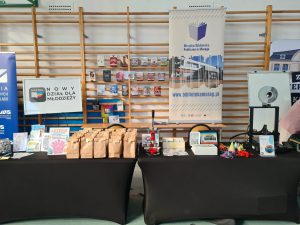 Stoisko Miejskiej Biblioteki Publicznej w Morągu z książkami, materiałami promocyjnymi i drukarką 3D.