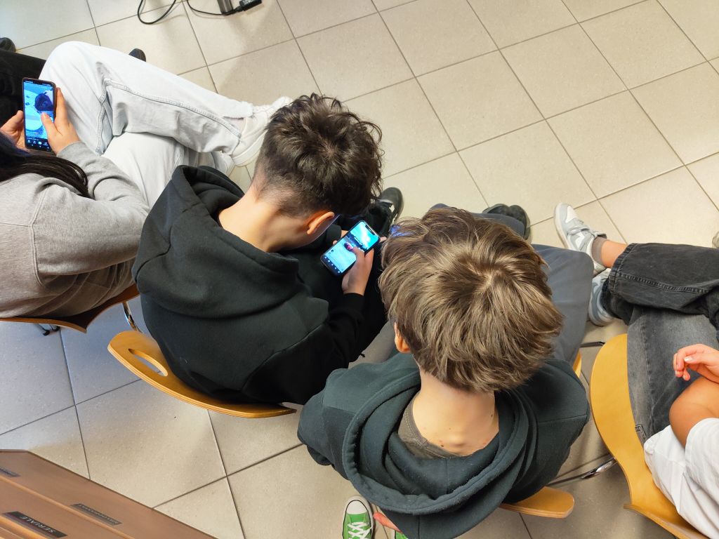 Widok z góry na dwoje nastolatków patrzących w ekran smartfona.