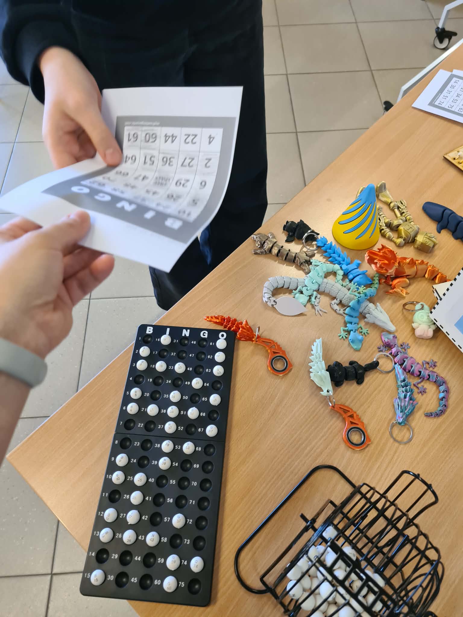 Na stole leżą plansza do bingo, losy oraz kolorowe wydruki 3D wykorzystywane podczas zajęć.