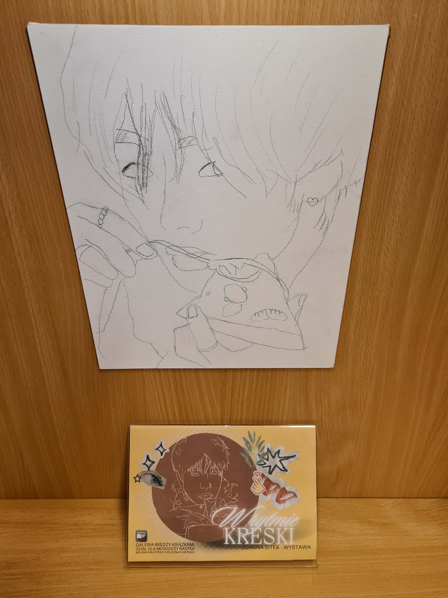 Szkic portretowy na płótnie przedstawiający osobę trzymającą filiżankę, poniżej tabliczka informacyjna wystawy „W rytmie kreski”