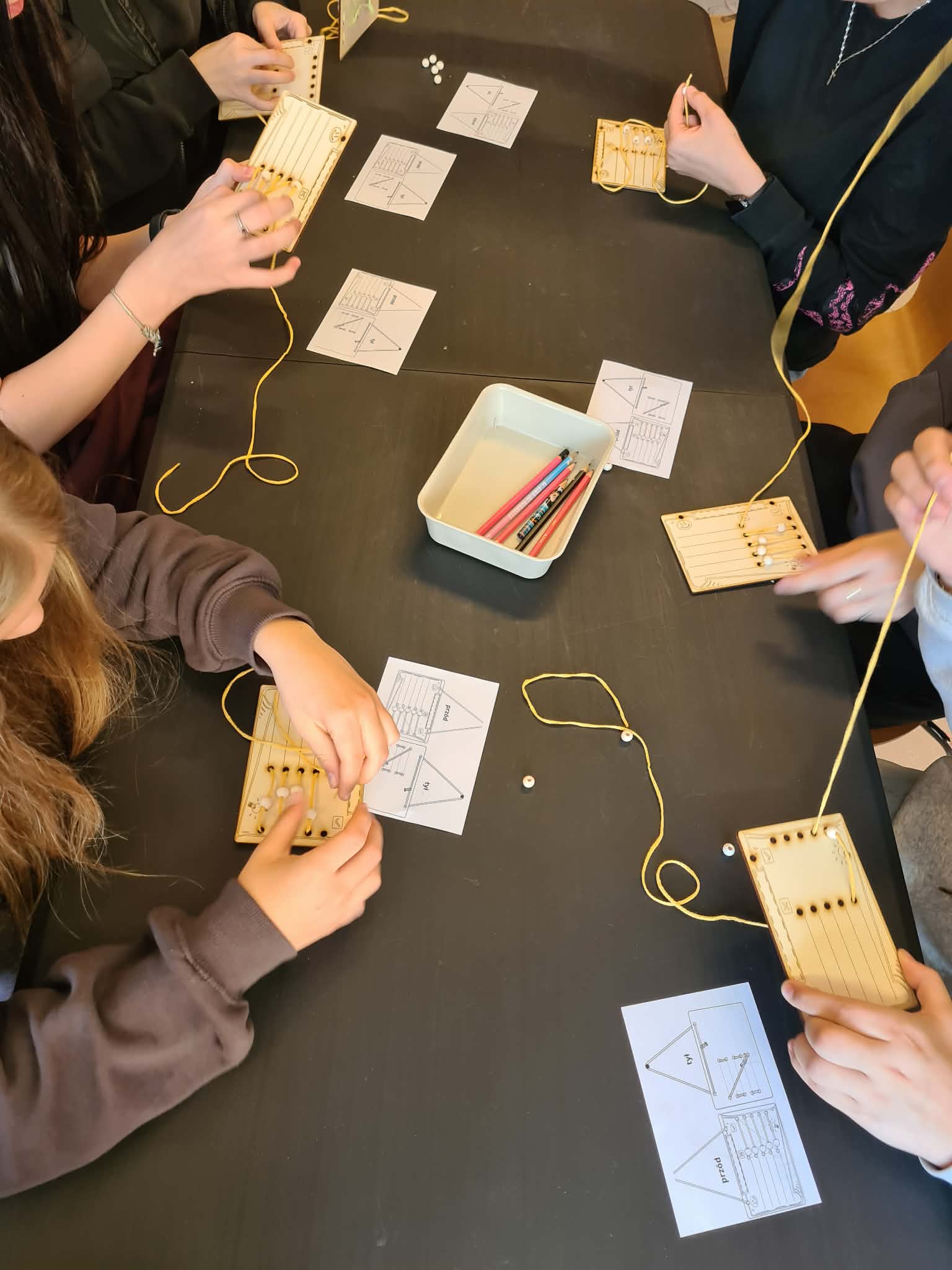 Młodzież pracuje przy stole z pomocami do ćwiczenia planowania i ustalania priorytetów.