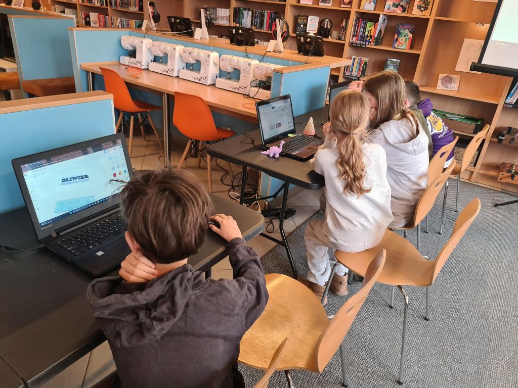 Dzieci projektują napisy i modele 3D na laptopach podczas zajęć.