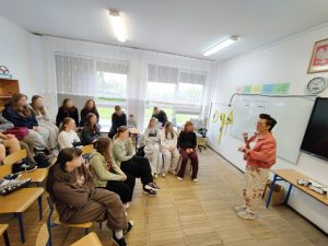 Grupa uczniów uczestniczy w zajęciach o organizacji czasu. Bibliotekarka stoi przy tablicy, na której przygotowano matrycę Eisenhowera.