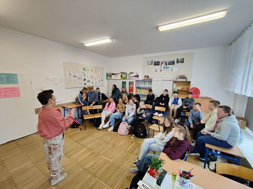 Bibliotekarka prowadzi zajęcia z zarządzania czasem w sali lekcyjnej. Uczniowie siedzą na krzesłach i ławkach, słuchając prowadzącej.