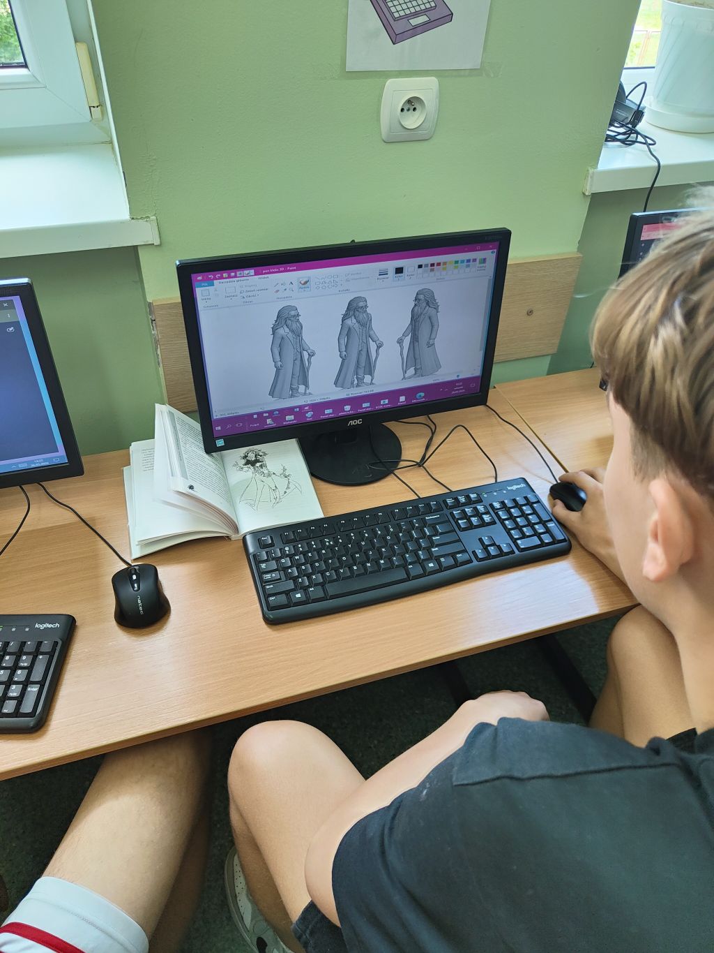 Uczeń przy komputerze ogląda wygenerowany model 3D postaci inspirowanej opisem z książki. Obok monitora leży otwarta książka jako źródło inspiracji.