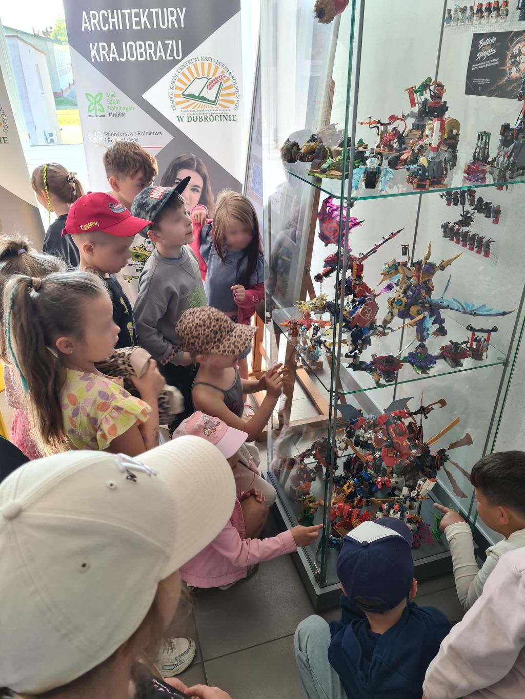 Przedszkolaki oglądają wystawę klocków LEGO Ninjago w gablocie lokalnych pasjonatów.