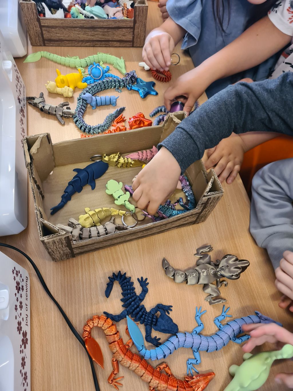 Dzieci wybierają kolorowe figurki i breloki wydrukowane w technologii 3D.