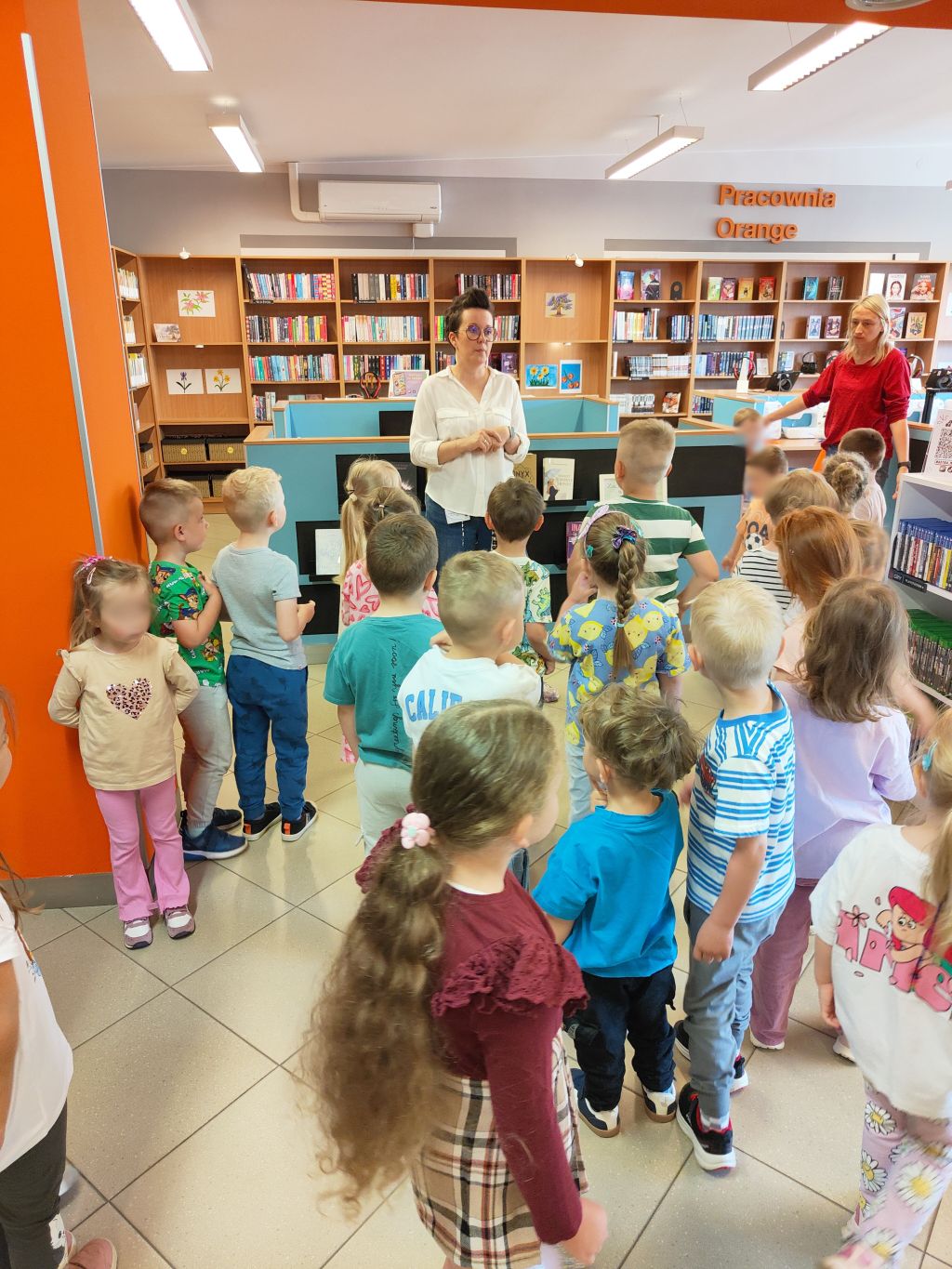 Grupa dzieci zwiedza Pracownię Orange w bibliotece.