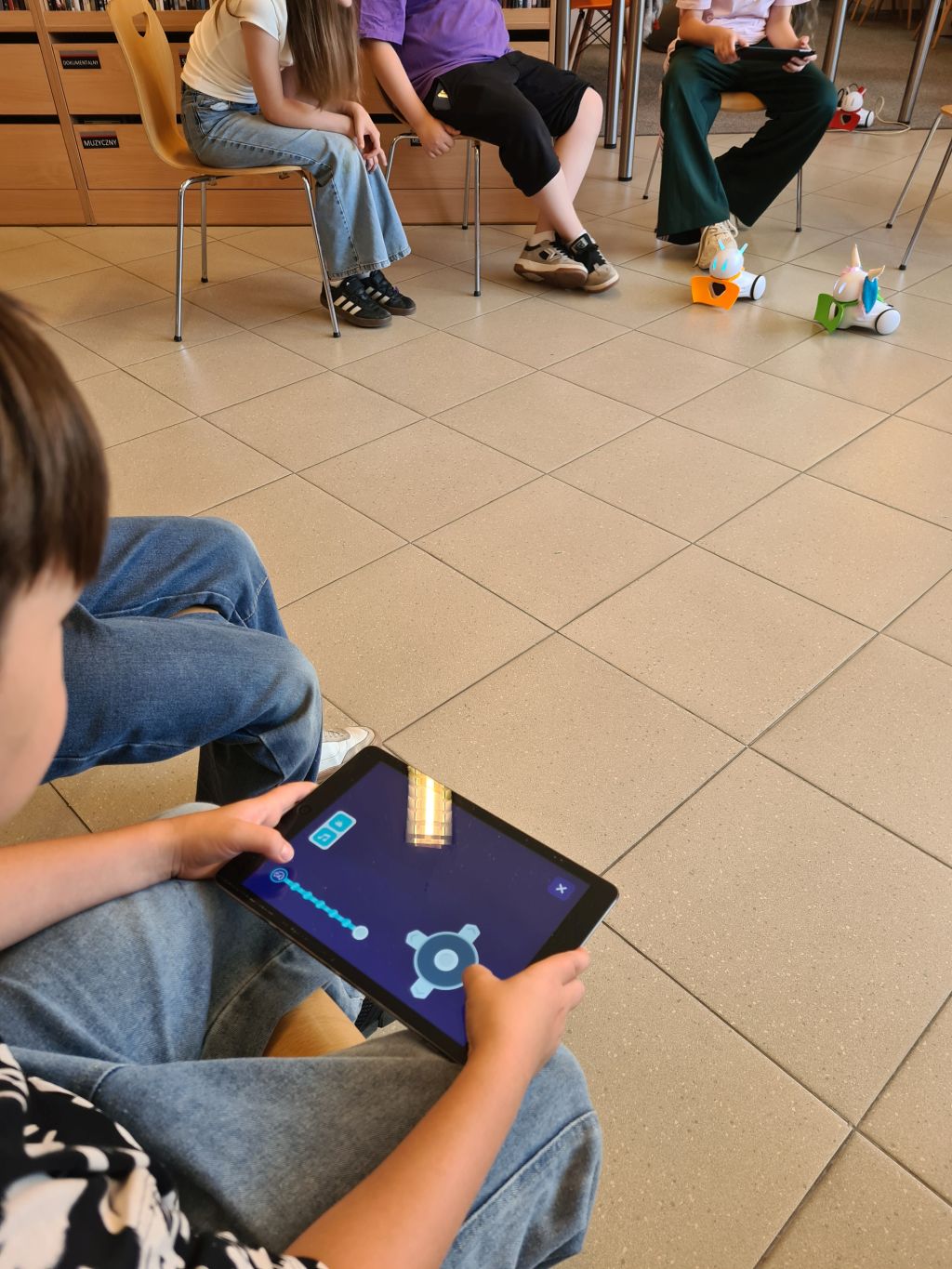 Uczestnik steruje robotami za pomocą tabletu.