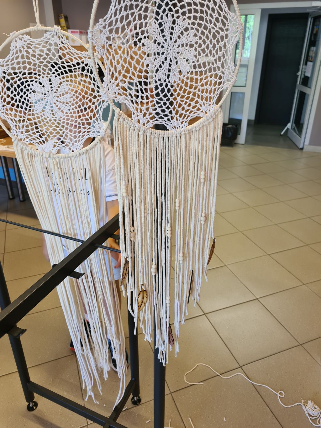 Dwa gotowe łapacze snów ozdobione długimi frędzlami, drewnianymi koralikami i zawieszkami w kształcie piór.