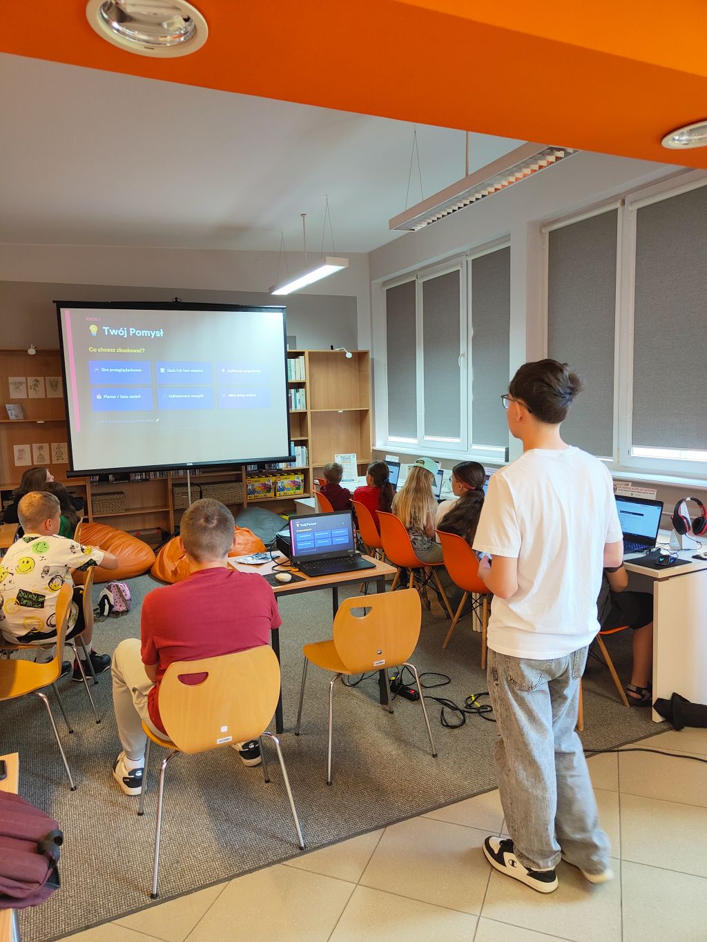 Sala edukacyjna z projektorem wyświetlającym prezentację zatytułowaną 