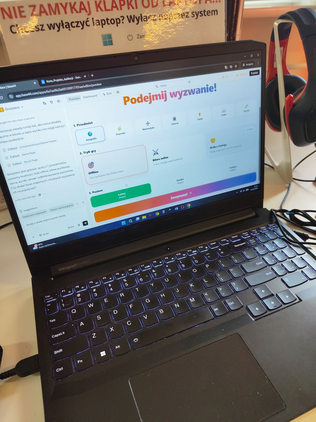 Zbliżenie na laptopa wyświetlającego platformę edukacyjną z quizami online pod hasłem „Podejmij wyzwanie!”.